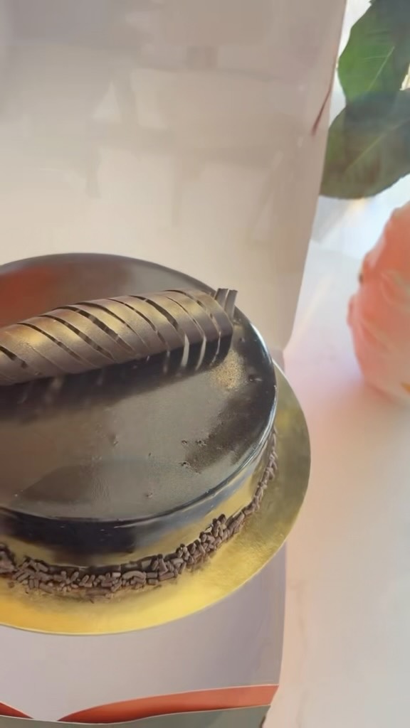Glossy chocolate mousse cake with a curled chocolate garnish