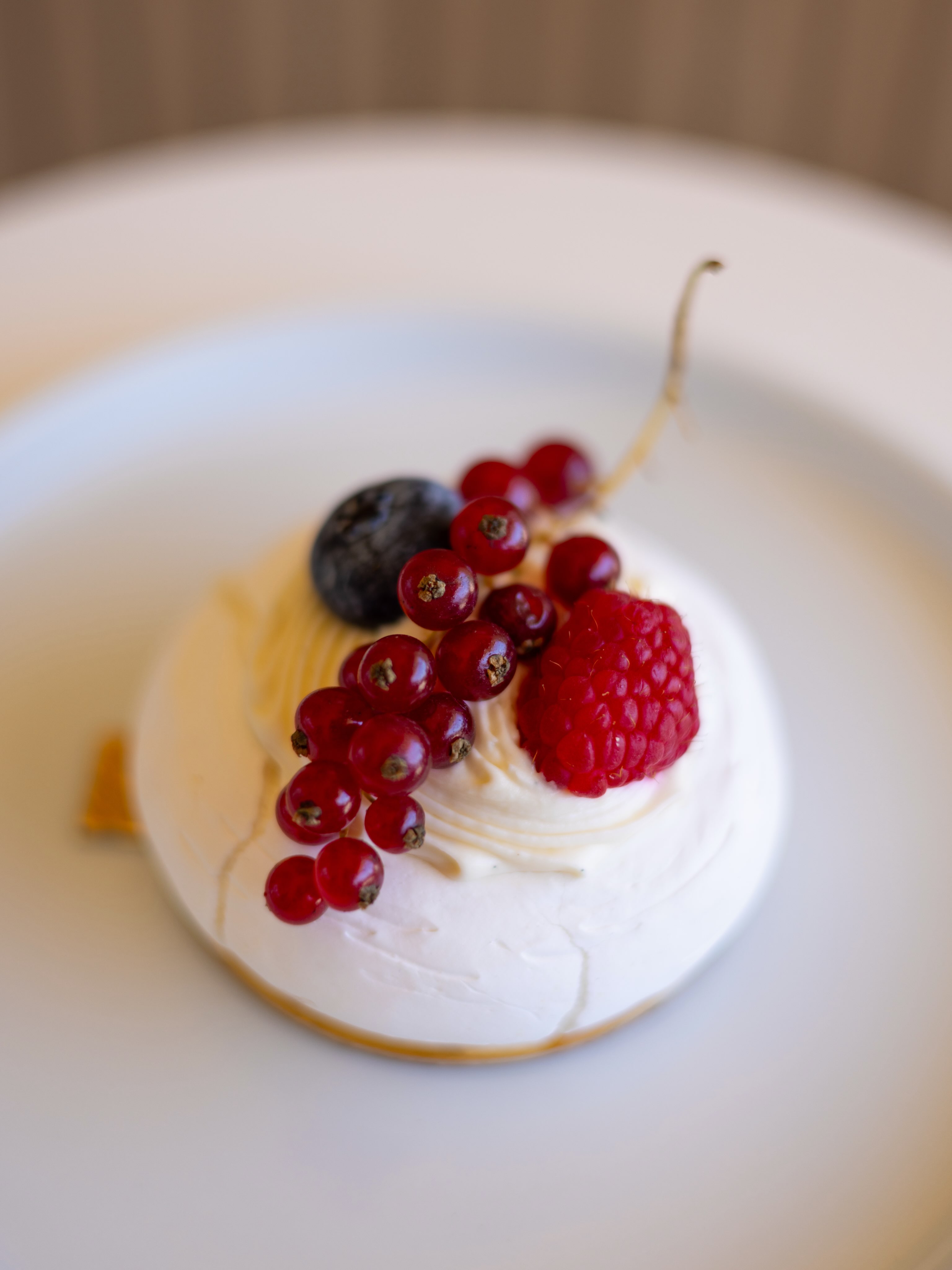 Individual pavlova topped with raspberries, currants, and blueberry